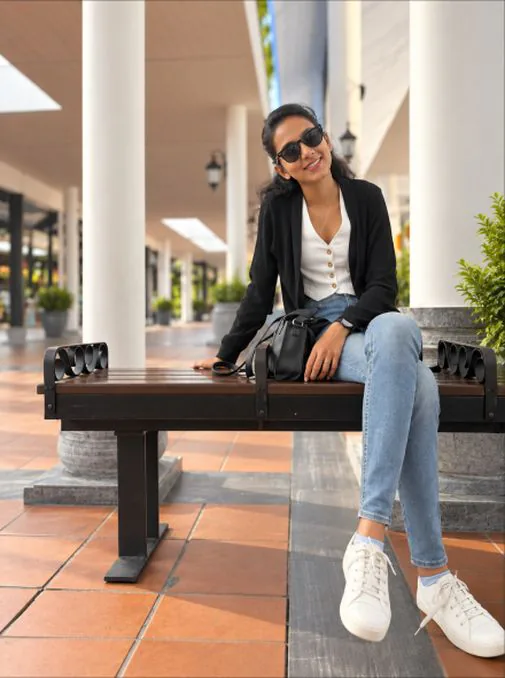 Atshaya smiling on a bench in a sunlit colonnade